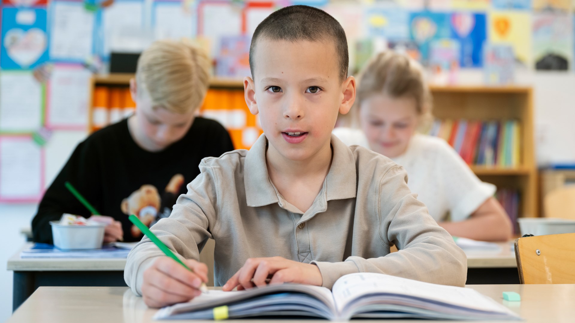 Pojke i klassrum håller i en penna