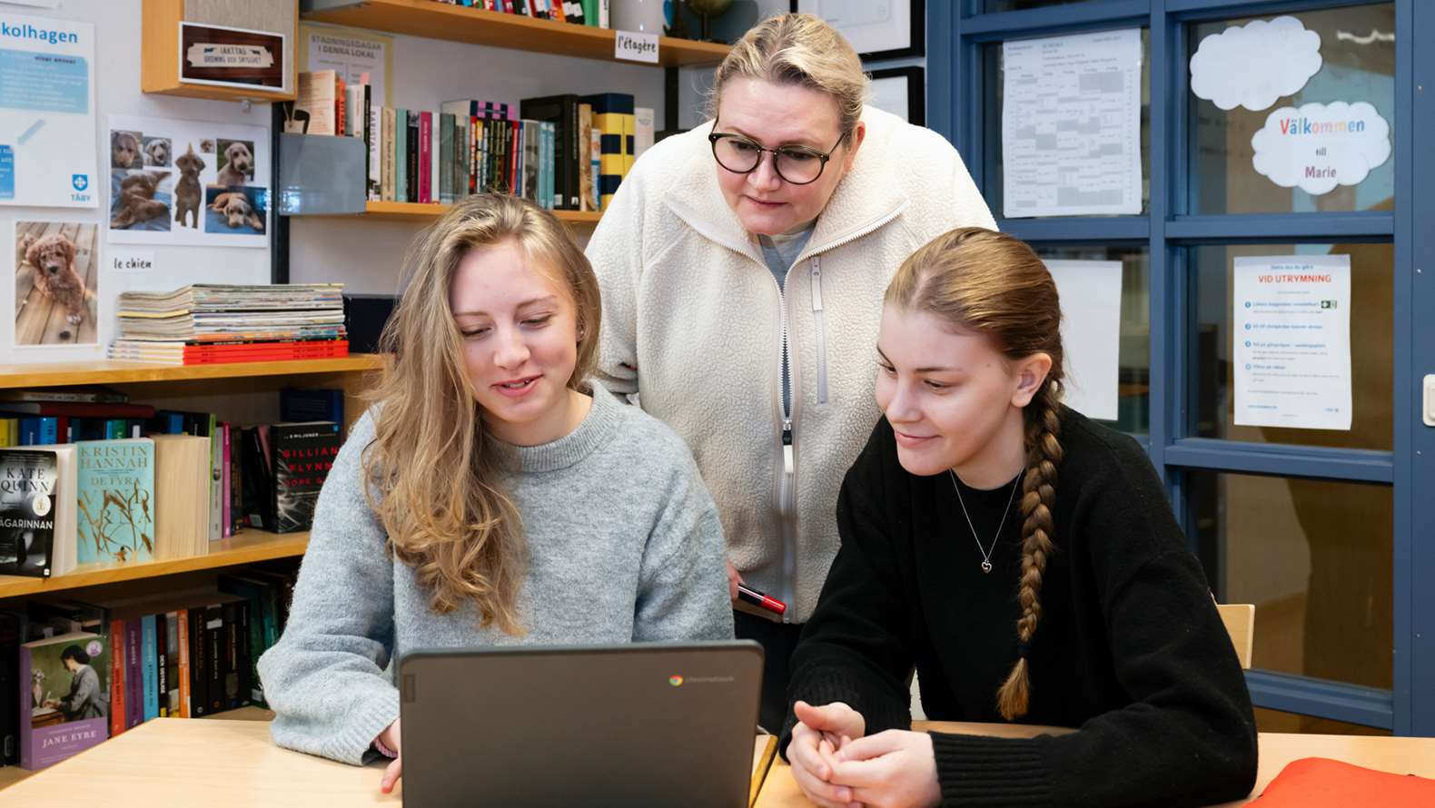 Lärare hjälper två elever med bärbar dator