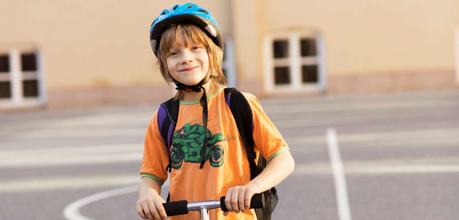 Pojke med cykelhjälm håller i en sparkcykel