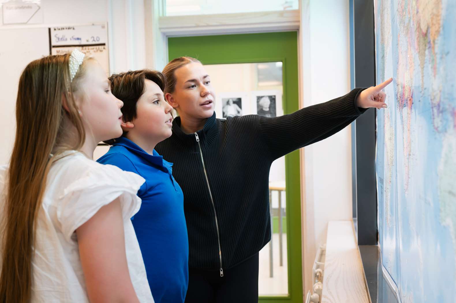 Lärare visar på tavlan för två elever