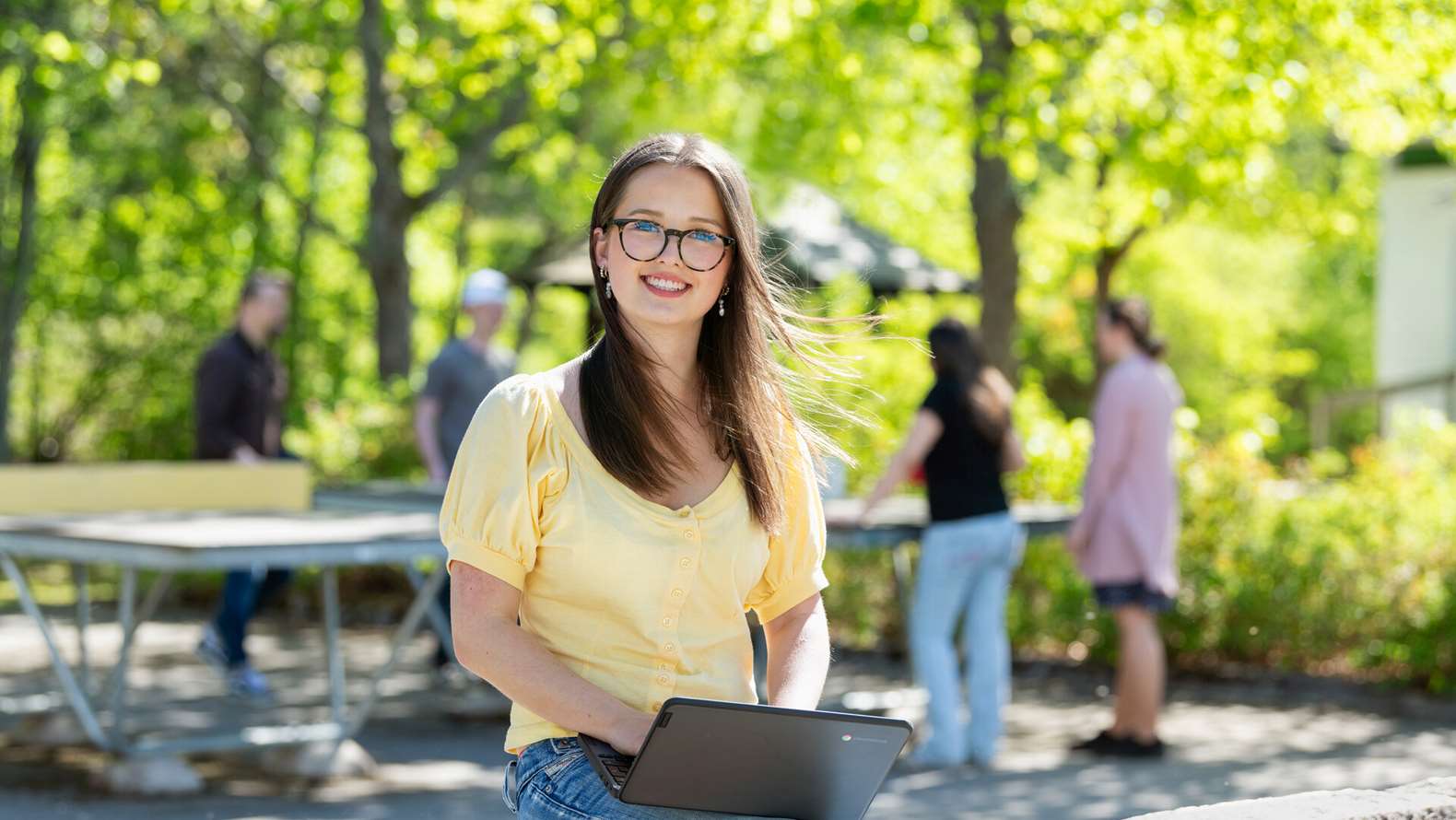 Flicka sitter med bärbar dator på skolgård