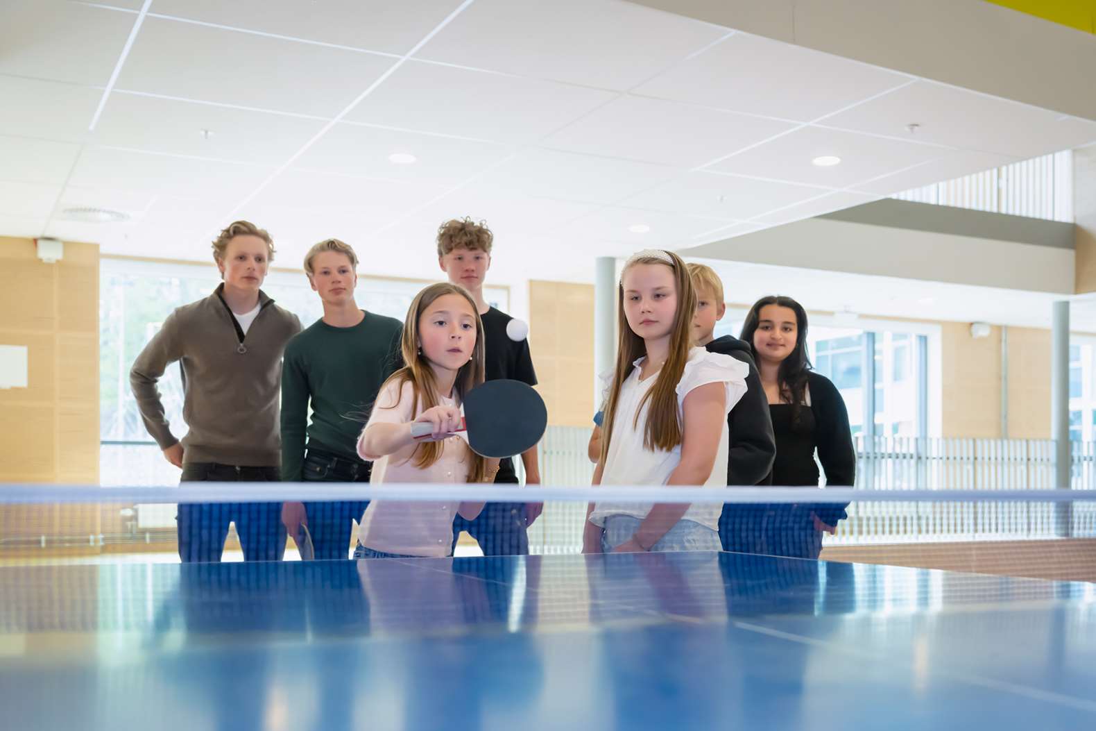 En grupp elever samlade vid ett pingisbord