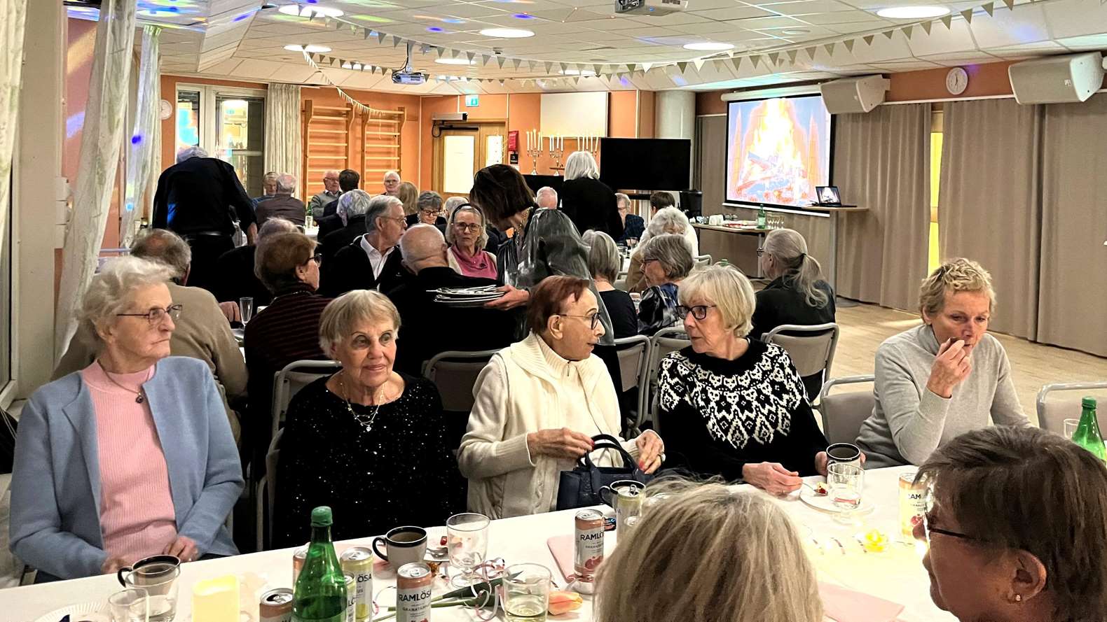 Flera personer sitter i en lokal och äter mat.