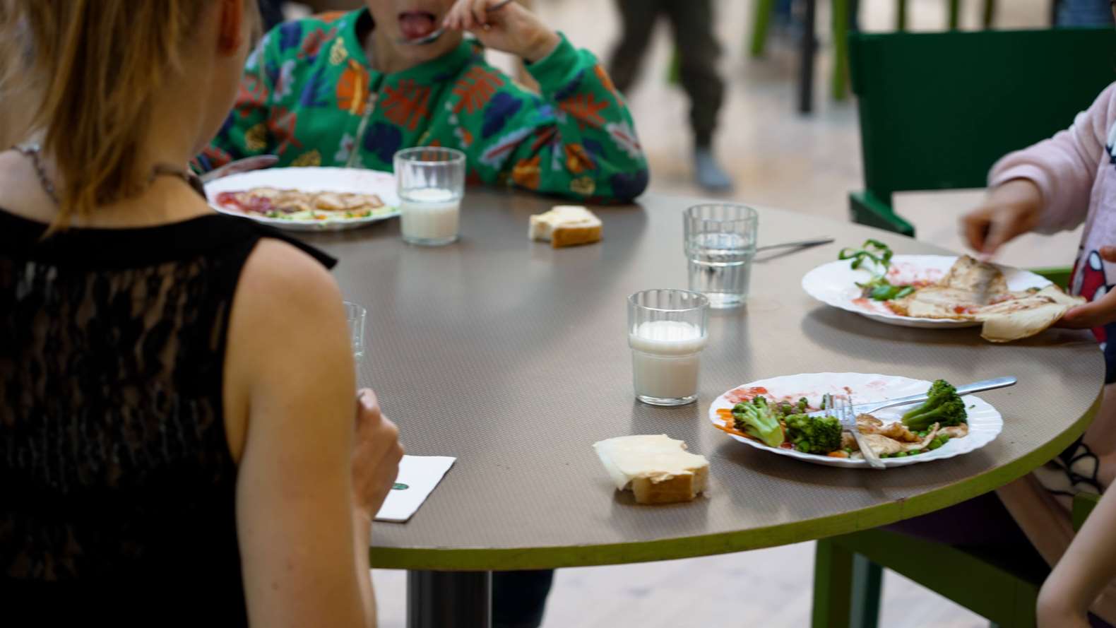 Barn sitter vid ett bord och äter skolmat