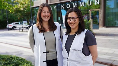 Två personer tittar in i kameran utomhus.